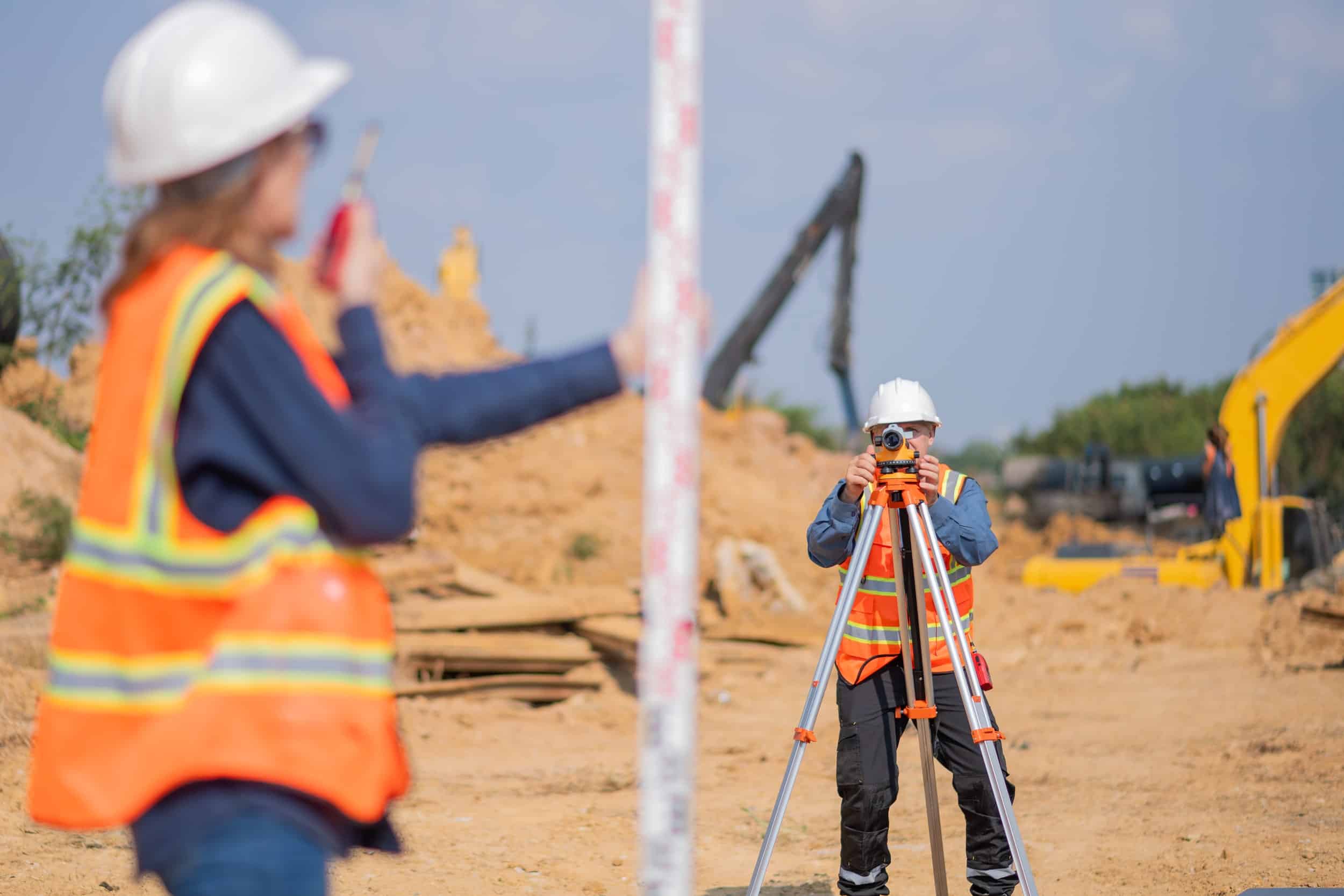 a man and woman in safety vests and helmets taking a picture of a construction site