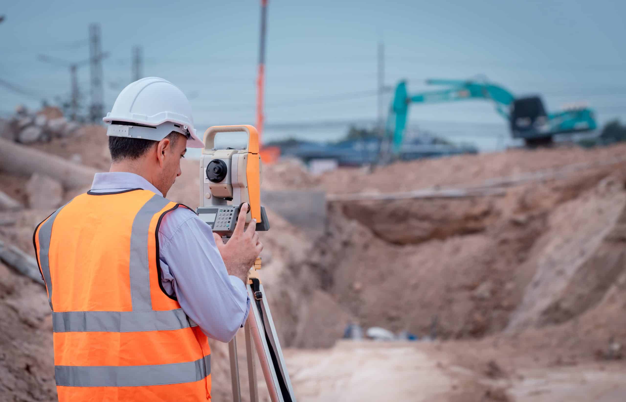a man in a hard hat using a theodolite
