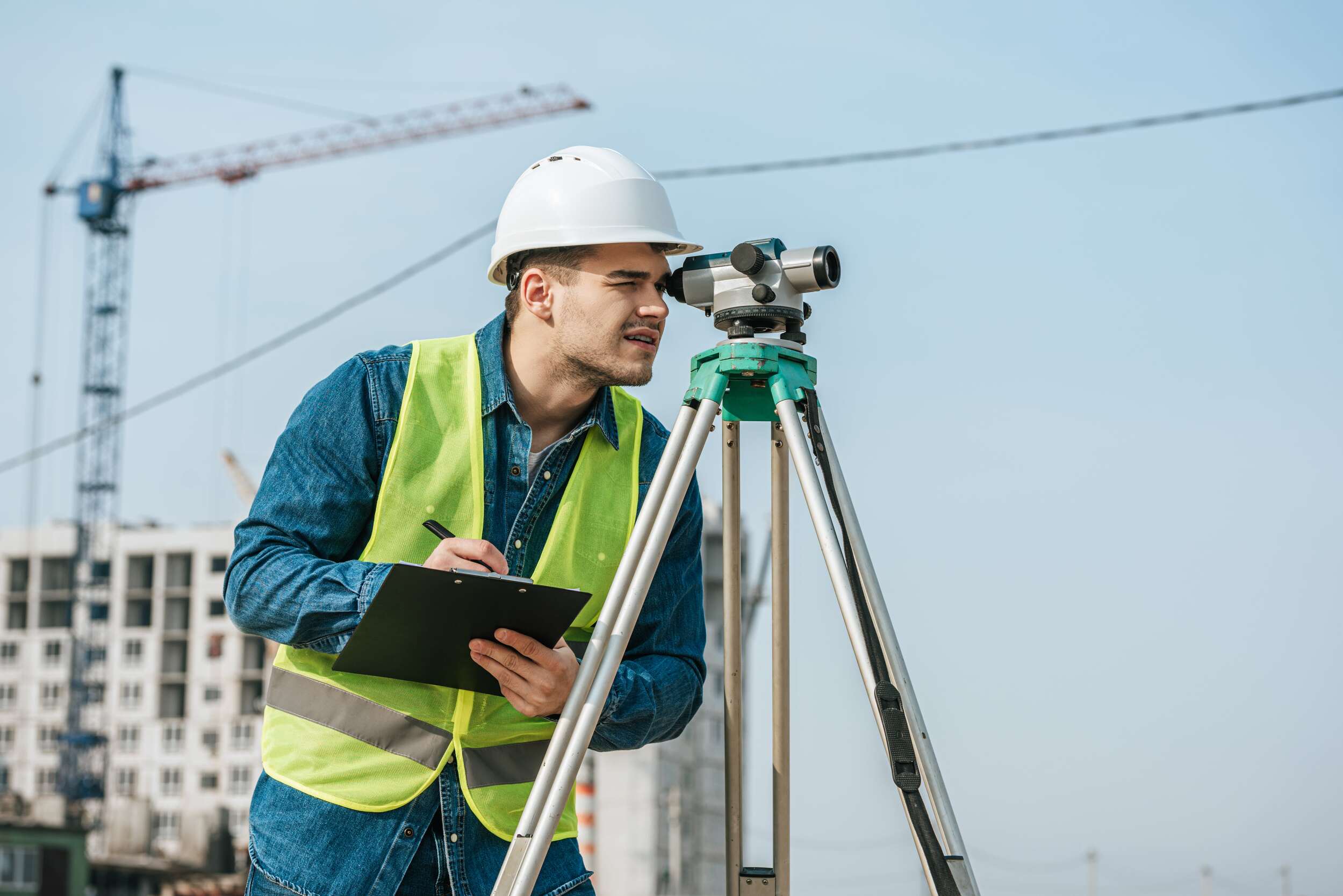 a man in a hard hat writing on a clipboard