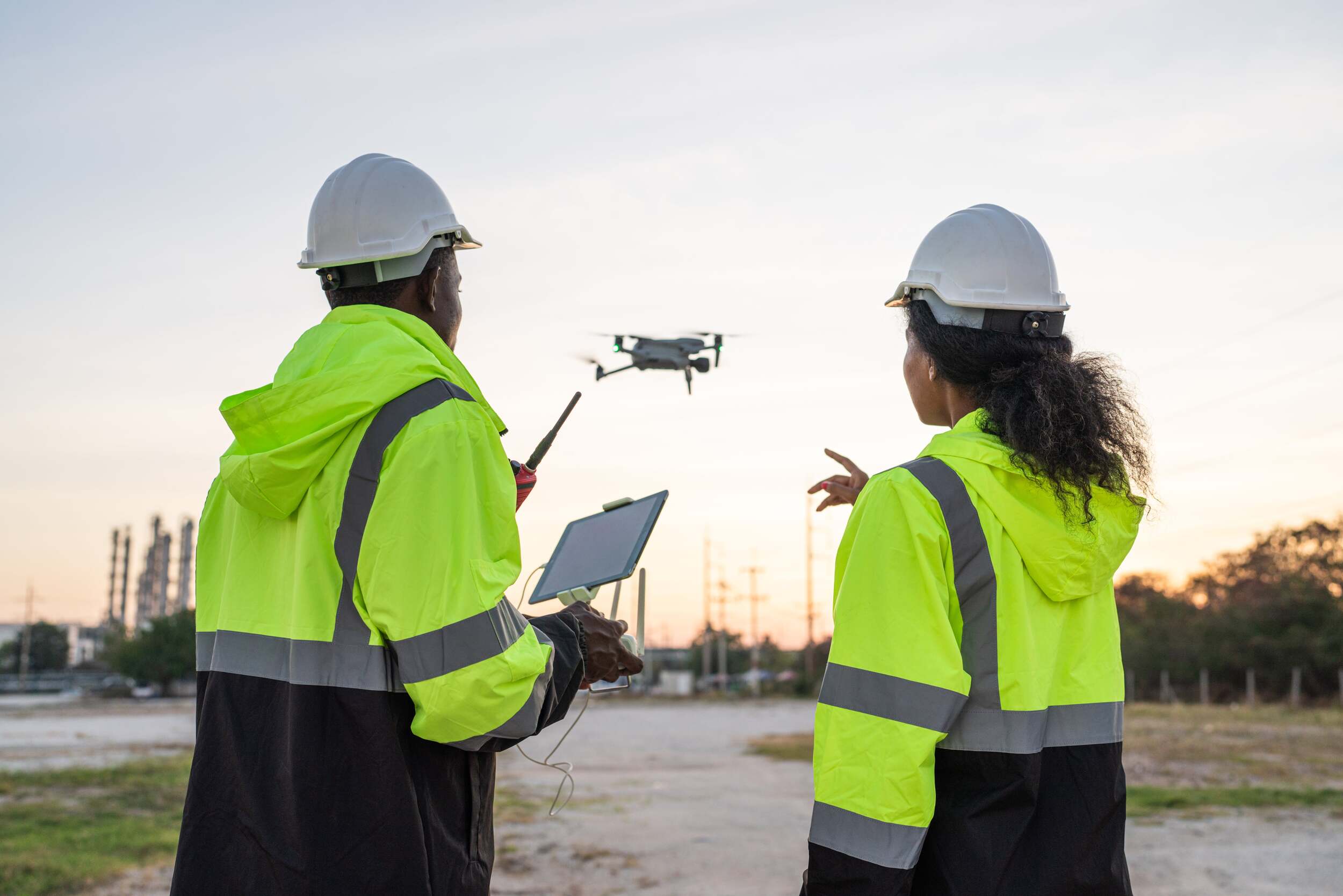 a group of people in safety jackets and helmets flying a drone
