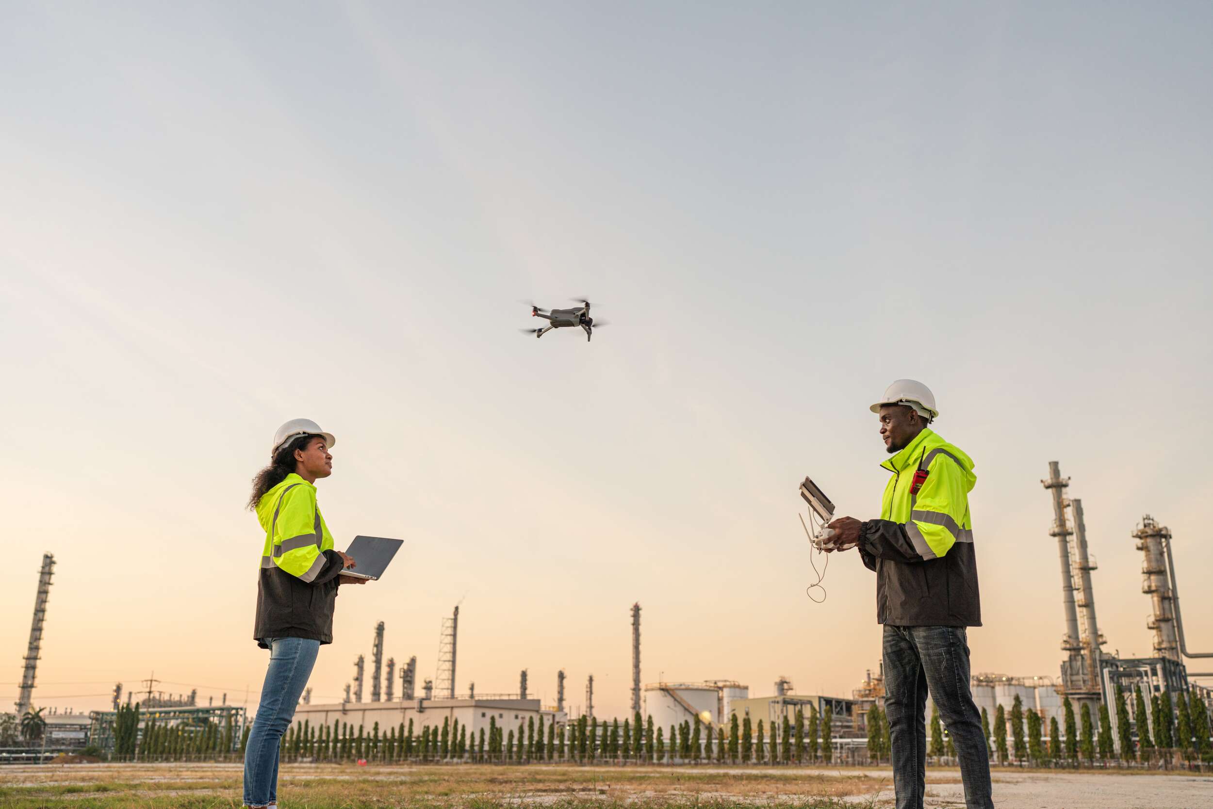 a man and woman in safety vests flying over a factory
